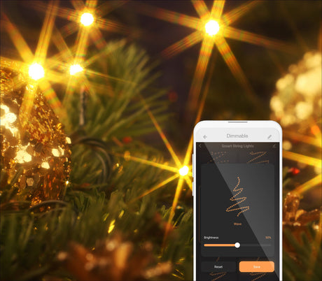 Weihnachtsbaum mit goldenen Lichtern und Dekoration, Smartphone mit App zur Steuerung der Lichter.