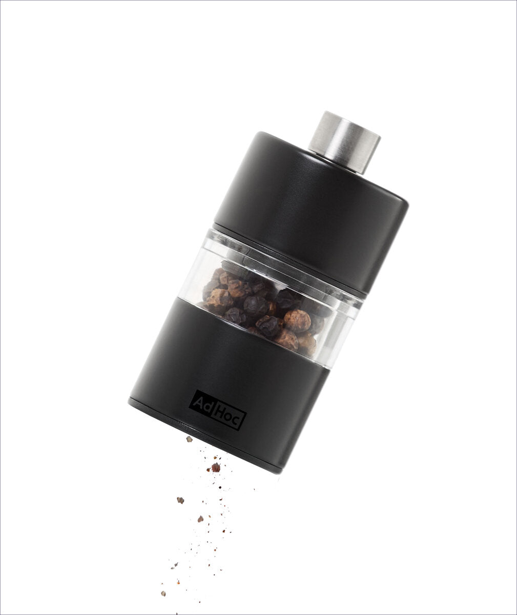 Elektrischer Pfeffermühle mit schwarzen Pfefferkörnern, die herausfallen.