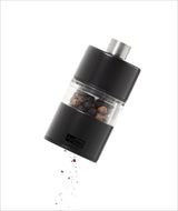 Elektrischer Pfeffermühle mit schwarzen Pfefferkörnern, die herausfallen.