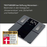 Digitale Personenwaage mit Gewichtsanzeige, Bewertung und Testurteil auf dem Bild.