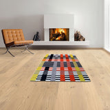 Moderner Raum mit Kamin, braunem Sessel, buntem geometrischem Teppich und Holzfußboden.