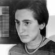 Schwarz-weißes Portrait einer Frau mit kurzen dunklen Haaren, trägt einen Pullover und eine Halskette.