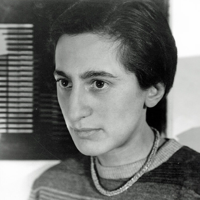 Schwarz-weißes Portrait einer Frau mit kurzen dunklen Haaren, Blick nach rechts, trägt einen Pullover und eine Halskette.