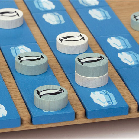 Brettspiel mit blauen Spielsteinen und runden weißen Figuren mit Pinguin- und Eisbär-Symbolen.