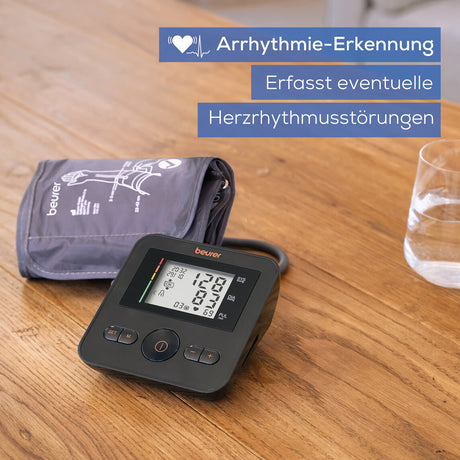 Blutdruckmessgerät, Blutdruckmanschette, Glas Wasser, Text über Arrhythmie-Erkennung und Herzrhythmusstörungen.