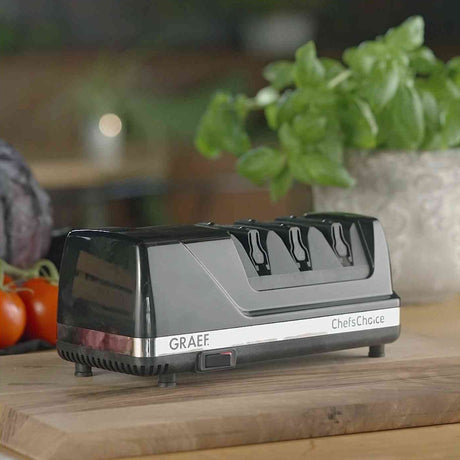 Elektro-Tacker auf Holzplatte, im Hintergrund Topf mit grüner Pflanze und Tomaten.