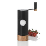 Salz- oder Pfeffermühle mit Holzbasis, schwarzem Gehäuse und Salz im Sichtfenster, neben Tomaten.