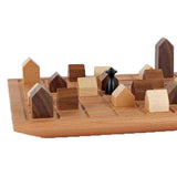 Holzspielzeug mit Häusern und einer schwarzen Spielfigur auf einem Brett.