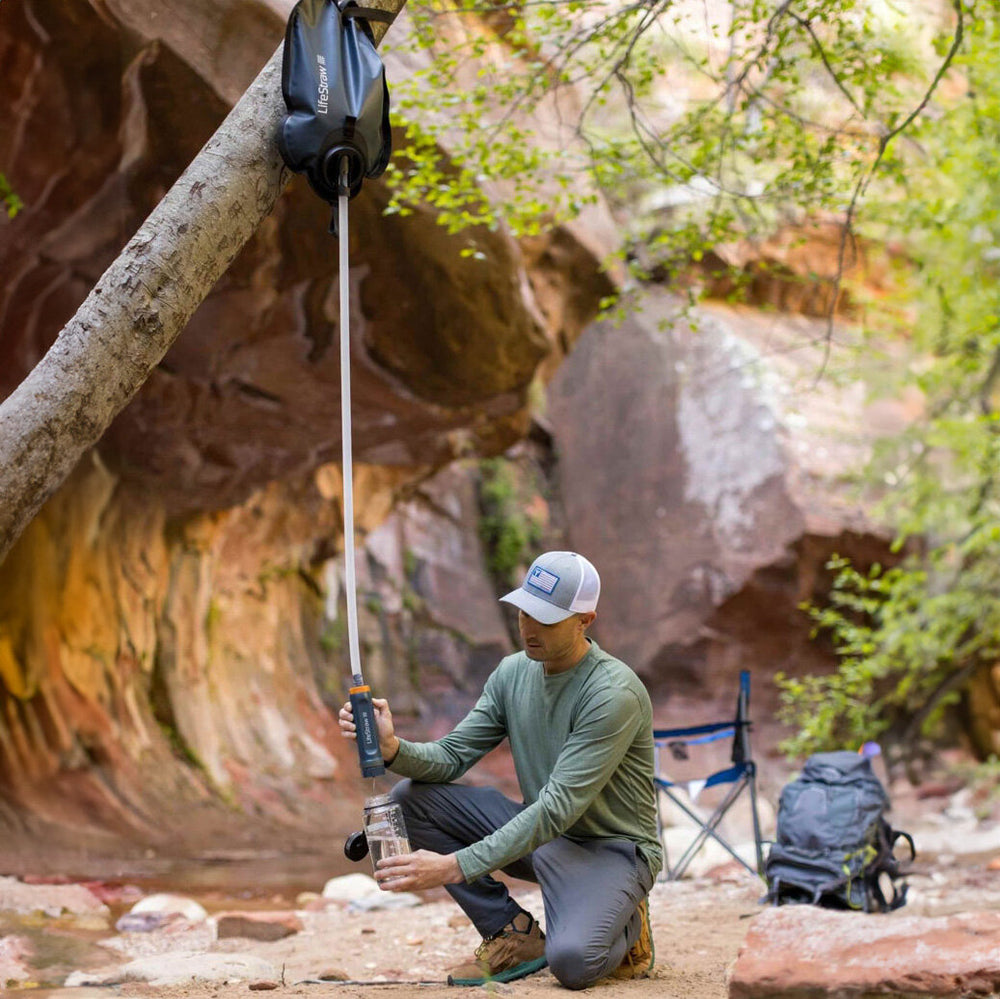 Mann füllt Wasserflasche mit LifeStraw aus einer Wasserquelle.