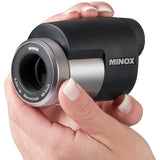 Hand hält Minox Makroskop mit schwarzem Gehäuse, silbernem Ring und Objektiv.