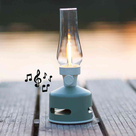 Kleiner Campingkocher mit Glühbirne, die wie eine Flamme leuchtet, auf Holz im Freien, mit Musiknoten daneben.