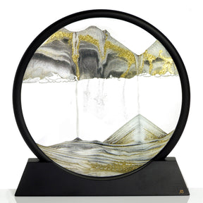 Schwarz-goldene Wanddekoration mit Berg- und Wasserfall-Motiv in einem runden Rahmen auf schwarzem Sockel.