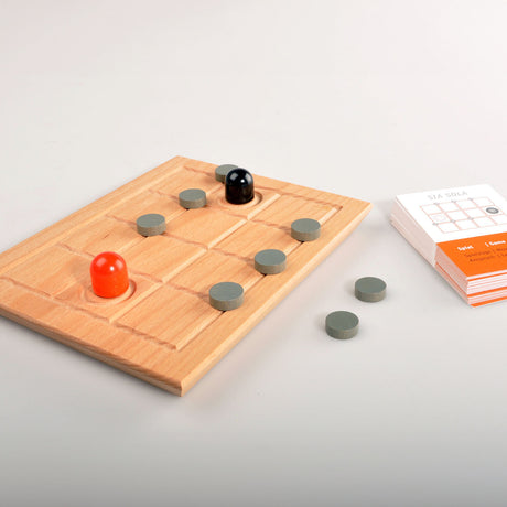 Holzbrett mit grauen Spielsteinen, einem schwarzen und einem roten Spielstein, Spielanleitung und Karten.