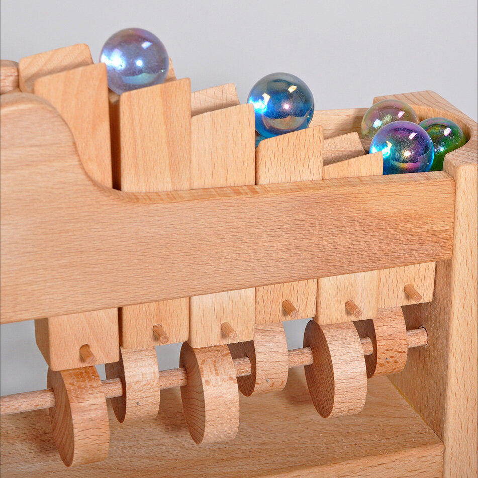 Holzspielzeug mit bunten Glaskugeln und beweglichen Holzrädern.