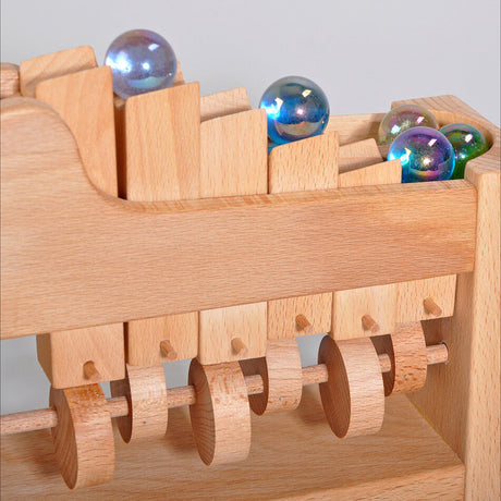 Holzspielzeug mit bunten Glaskugeln und beweglichen Holzrädern.