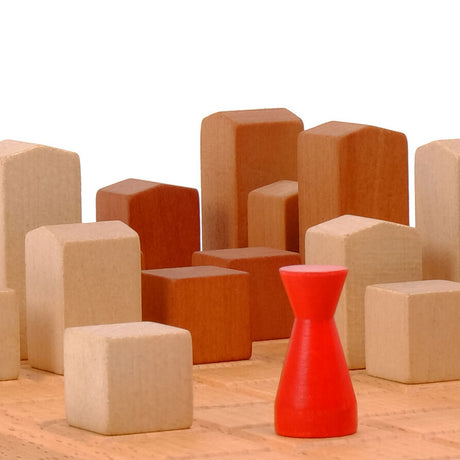 Verschiedene Holzklötze in Beige und Braun, sowie eine rote Holzfigur auf Holzboden.