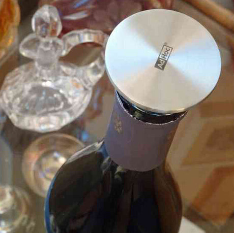 Blick auf den Flaschenhals eines dunklen Getränkeflasche mit silberner Kappe, im Hintergrund eine Kristallvase.
